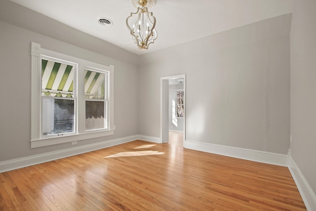 unfurnished room with hardwood / wood-style flooring and a notable chandelier