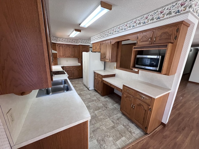 kitchen featuring sink, built in desk, a textured ceiling, and white fridge