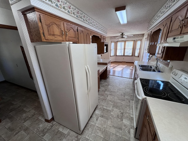 kitchen with ceiling fan, white appliances, sink, and a textured ceiling