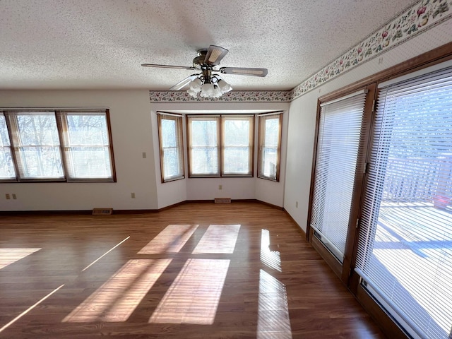 unfurnished room featuring ceiling fan, hardwood / wood-style flooring, plenty of natural light, and a textured ceiling