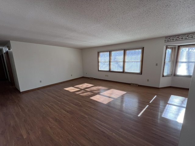 unfurnished room featuring a healthy amount of sunlight, a textured ceiling, and dark hardwood / wood-style floors