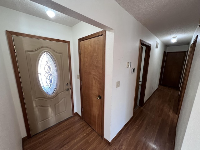 entryway featuring dark wood-type flooring and a textured ceiling