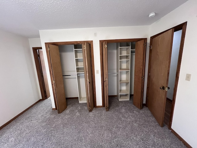 unfurnished bedroom with carpet, two closets, and a textured ceiling