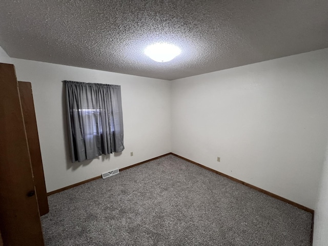 unfurnished room with dark colored carpet and a textured ceiling