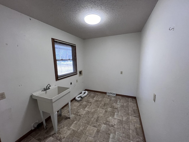 washroom featuring hookup for a washing machine and a textured ceiling