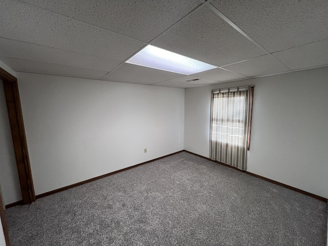 unfurnished room with a paneled ceiling and carpet flooring