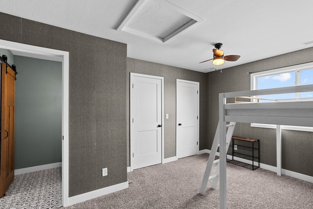 carpeted bedroom featuring a barn door and ceiling fan