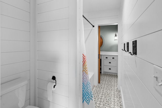 bathroom featuring toilet and wood walls