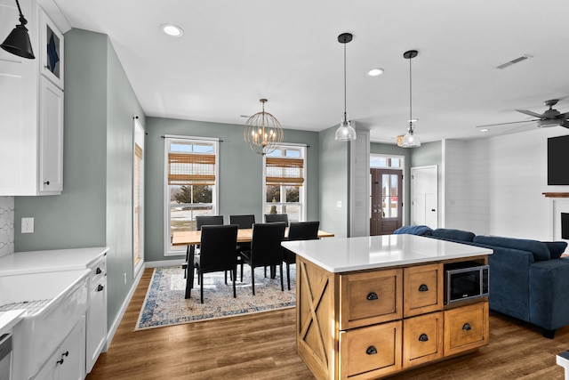 kitchen featuring dark hardwood / wood-style flooring, decorative light fixtures, white cabinets, and a kitchen island