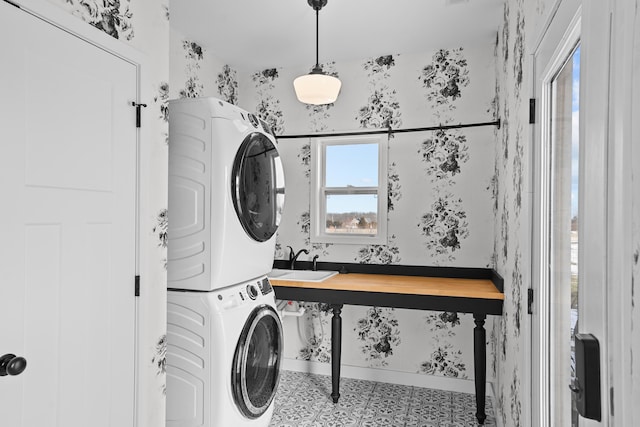 laundry room with tile patterned flooring, stacked washer and clothes dryer, and sink