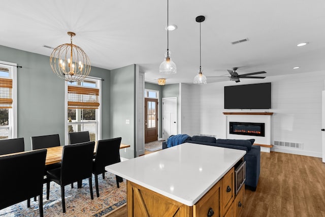 kitchen with pendant lighting, ceiling fan, wood-type flooring, and a center island