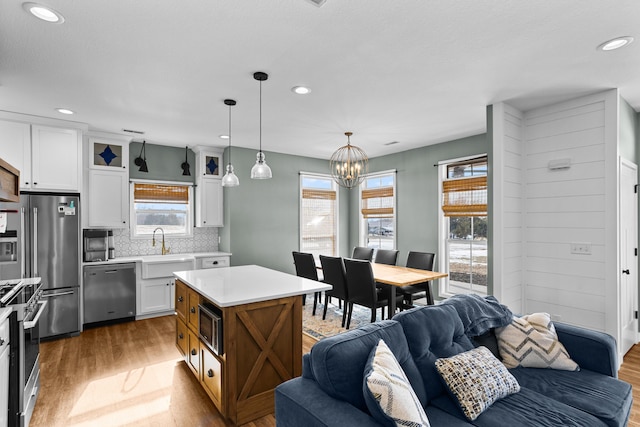 kitchen with white cabinets, hanging light fixtures, a center island, stainless steel appliances, and dark wood-type flooring