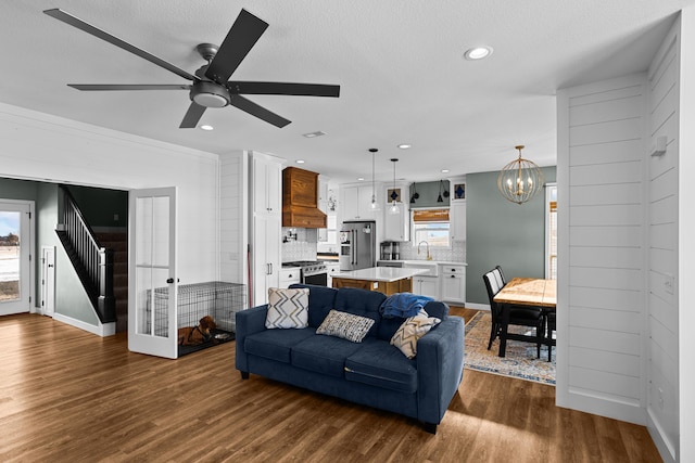 living room featuring ceiling fan with notable chandelier, dark hardwood / wood-style floors, and a textured ceiling