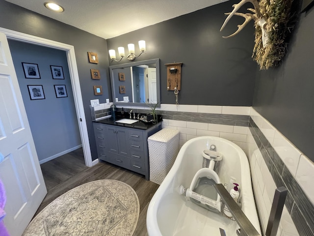 bathroom with vanity, hardwood / wood-style floors, a textured ceiling, and tiled tub