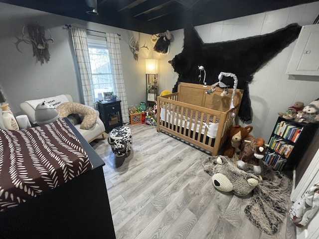 bedroom with a nursery area and light hardwood / wood-style floors