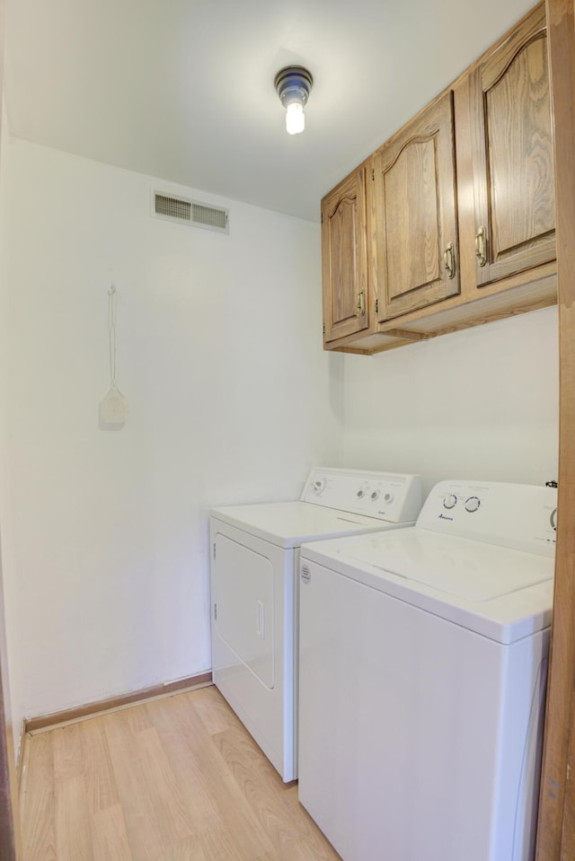 laundry area featuring cabinets, separate washer and dryer, and light hardwood / wood-style floors