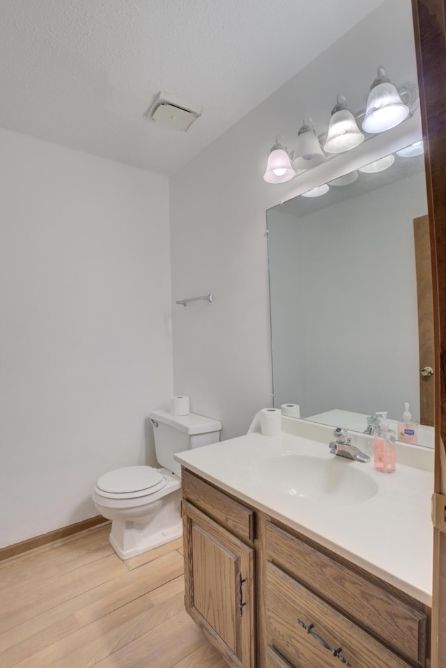 bathroom with hardwood / wood-style flooring, vanity, toilet, and a textured ceiling