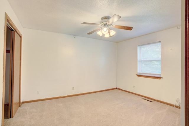 spare room with light carpet, a textured ceiling, and ceiling fan