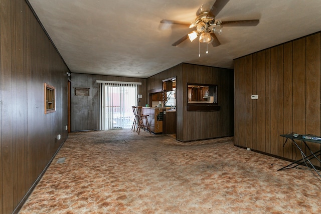 unfurnished living room with ceiling fan and wooden walls