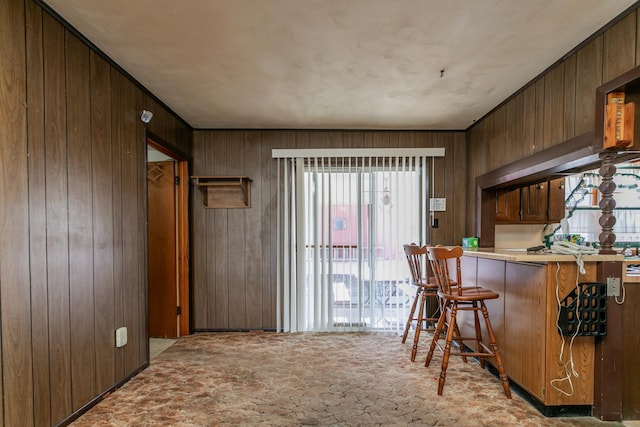 kitchen with a kitchen bar, light carpet, and wooden walls