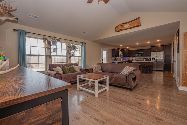 living room featuring vaulted ceiling, ceiling fan, and light hardwood / wood-style flooring