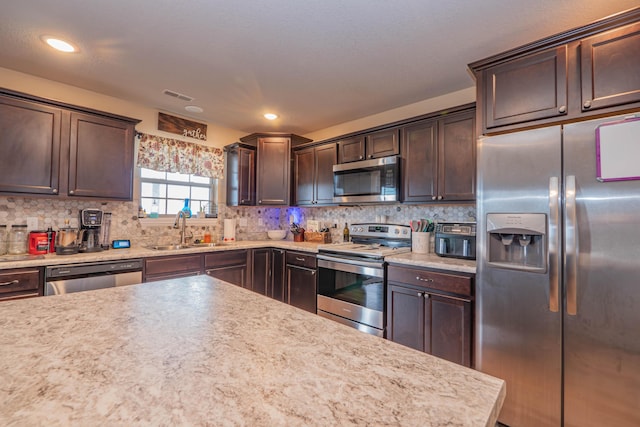 kitchen featuring appliances with stainless steel finishes, sink, dark brown cabinetry, and decorative backsplash