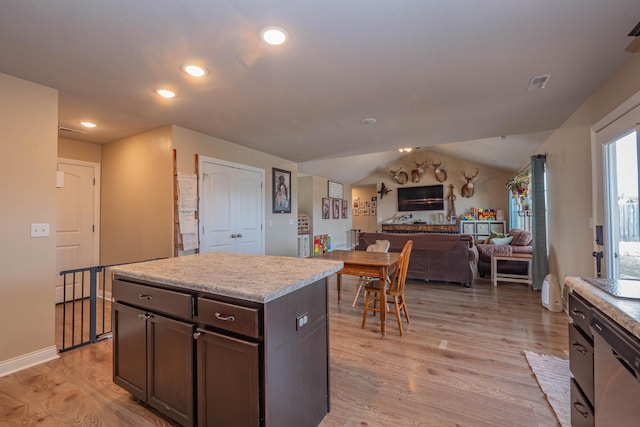 kitchen featuring dark brown cabinets, a center island, stainless steel dishwasher, and light hardwood / wood-style flooring