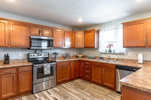 kitchen featuring appliances with stainless steel finishes, sink, and light hardwood / wood-style flooring