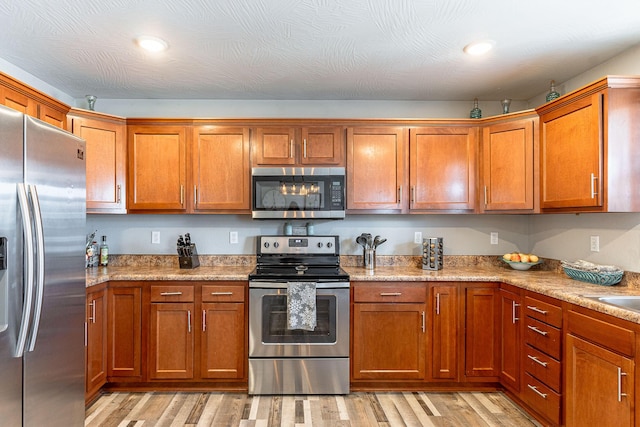 kitchen featuring appliances with stainless steel finishes, light stone counters, and light hardwood / wood-style floors