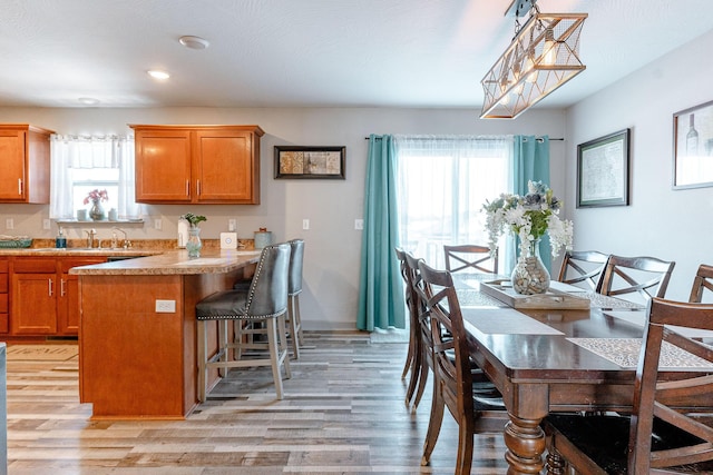 kitchen featuring a wealth of natural light, light wood-type flooring, pendant lighting, and a kitchen breakfast bar