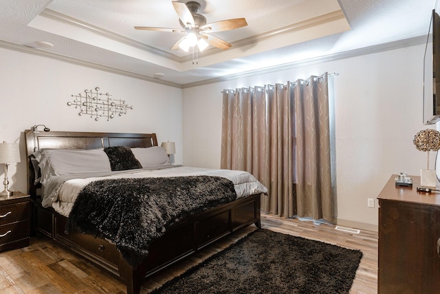 bedroom with wood-type flooring, a raised ceiling, and ceiling fan