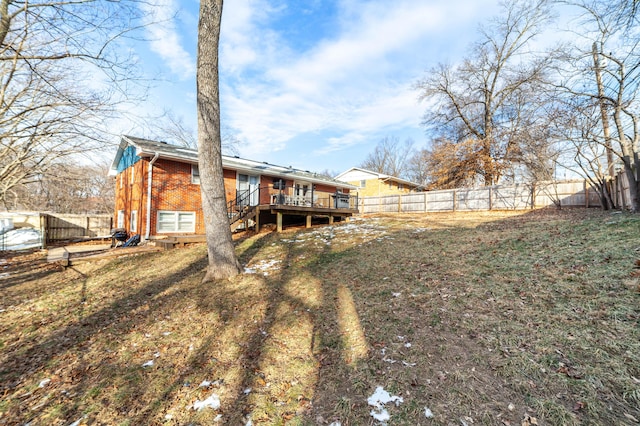 rear view of property with a wooden deck and a lawn