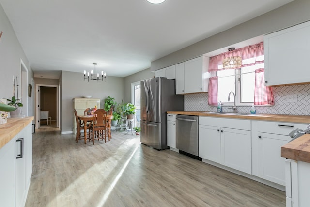 kitchen featuring wood counters, sink, white cabinetry, hanging light fixtures, and appliances with stainless steel finishes