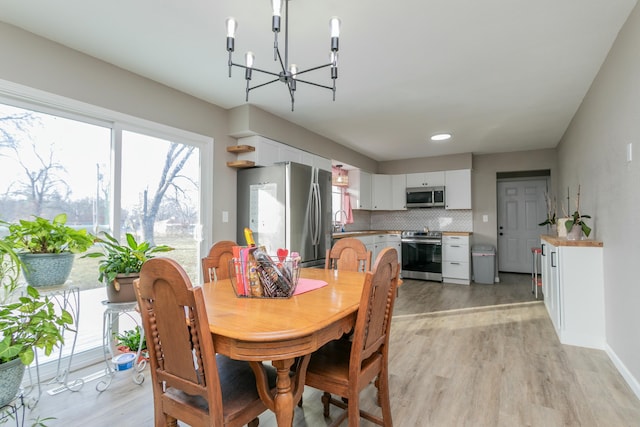 dining area with a chandelier, sink, and light hardwood / wood-style flooring