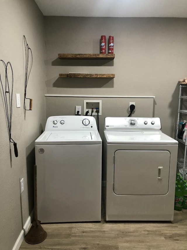 laundry area with washing machine and clothes dryer and light hardwood / wood-style floors