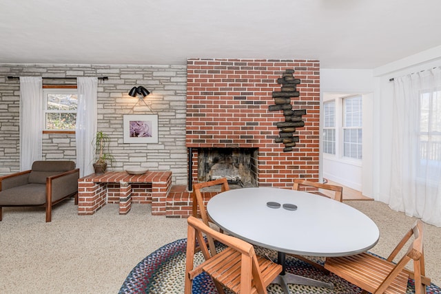 dining room with a large fireplace, a healthy amount of sunlight, and carpet flooring