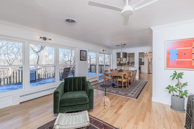 interior space featuring baseboard heating, crown molding, and light wood-type flooring