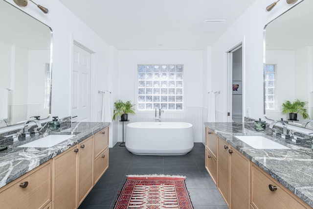 bathroom with vanity, tile patterned flooring, tile walls, and a tub