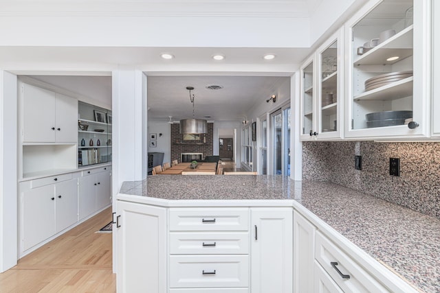 kitchen with decorative light fixtures, kitchen peninsula, a brick fireplace, and white cabinets