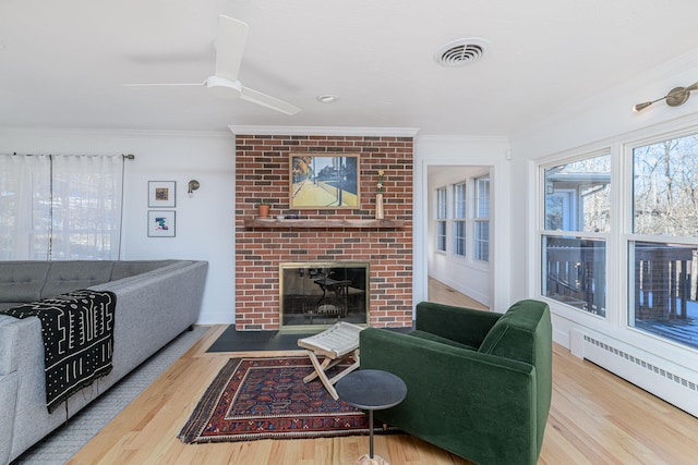 living room with ornamental molding, wood-type flooring, a baseboard heating unit, and a fireplace