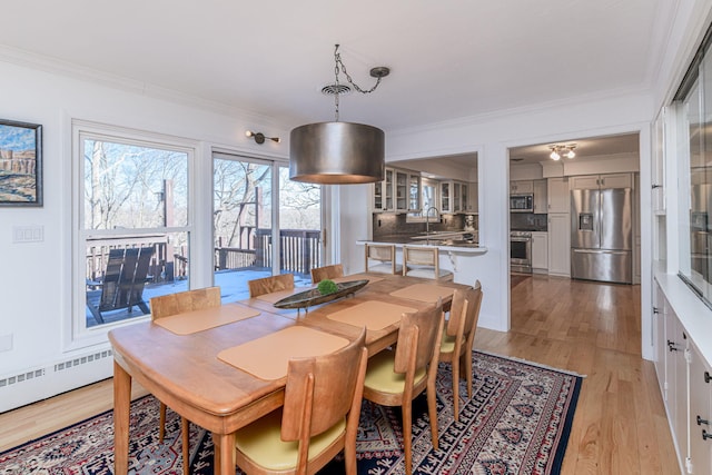 dining space with sink, crown molding, light hardwood / wood-style floors, and baseboard heating