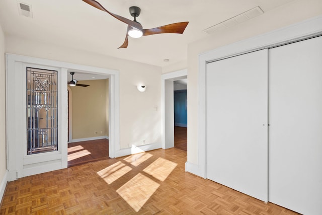 unfurnished bedroom with ceiling fan, light parquet flooring, and a closet