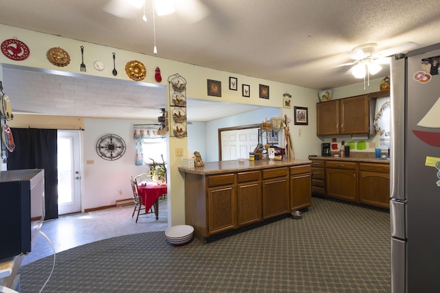 kitchen with stainless steel refrigerator, ceiling fan, a textured ceiling, dark carpet, and kitchen peninsula