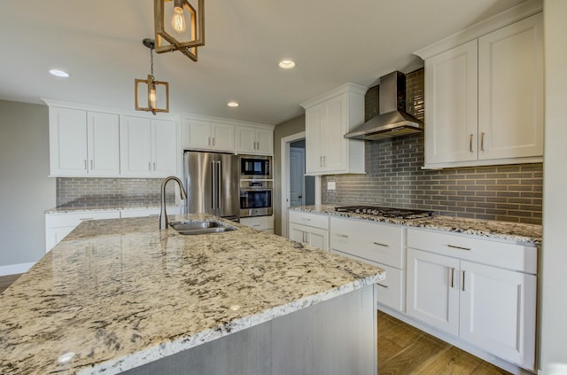 kitchen with wall chimney exhaust hood, sink, hanging light fixtures, appliances with stainless steel finishes, and white cabinets