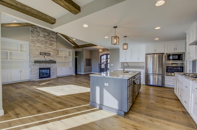 kitchen with pendant lighting, an island with sink, white cabinetry, sink, and stainless steel appliances