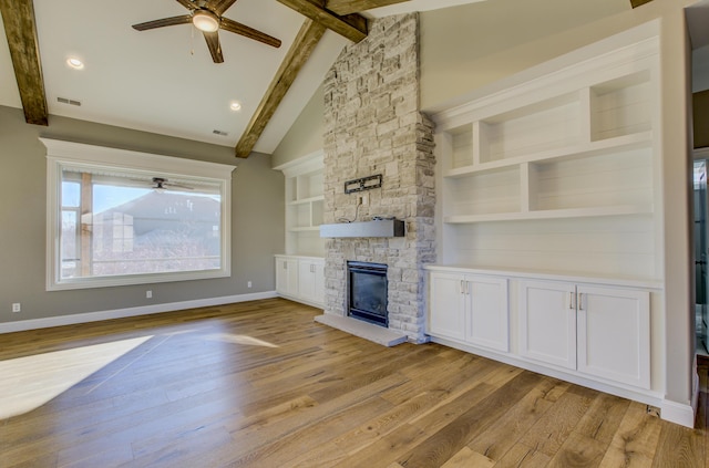 unfurnished living room with beam ceiling, high vaulted ceiling, ceiling fan, a fireplace, and light hardwood / wood-style floors