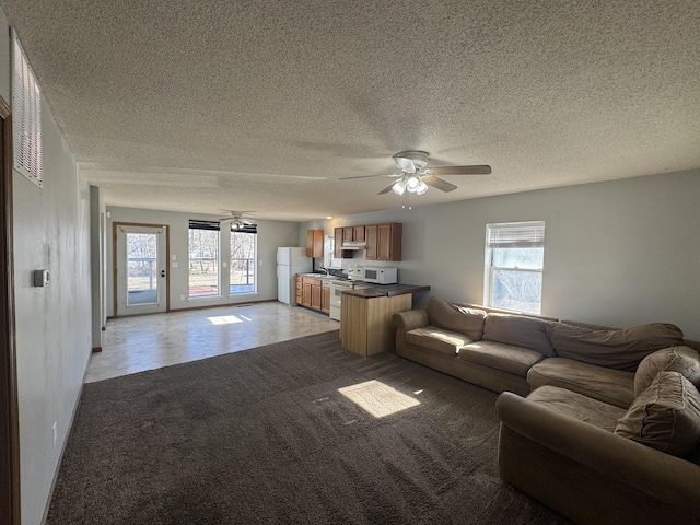 unfurnished living room featuring a healthy amount of sunlight, light colored carpet, and ceiling fan