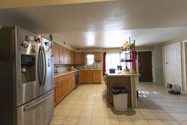 kitchen with light tile patterned flooring, appliances with stainless steel finishes, pendant lighting, sink, and a textured ceiling