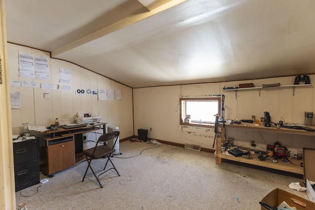 home office featuring a workshop area, lofted ceiling, light carpet, and wood walls