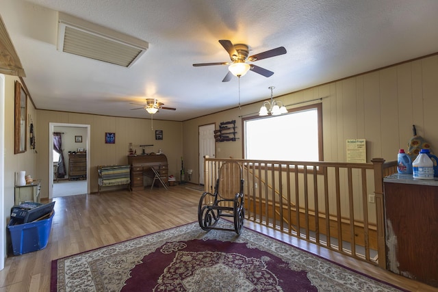 living area with hardwood / wood-style flooring, ornamental molding, a textured ceiling, and a chandelier